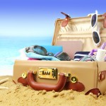 Full open suitcase on tropical beach background